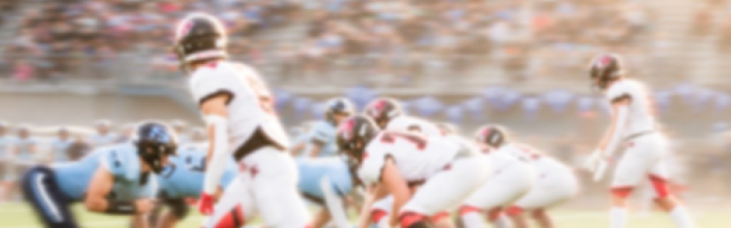Football players lined up at the line of scrimmage in front of full stands