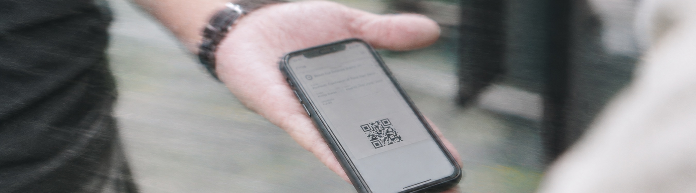 A hand holding a phone with a ticket QR code